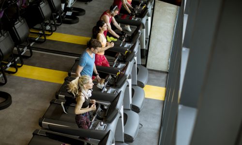 Top view at group of young people running on treadmills in modern gym